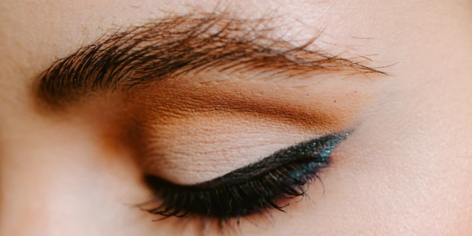 Geschlossenes Auge mit sorgfältig pigmentiertem Lidstrich als Teil einer Permanent-Make-up-Behandlung.